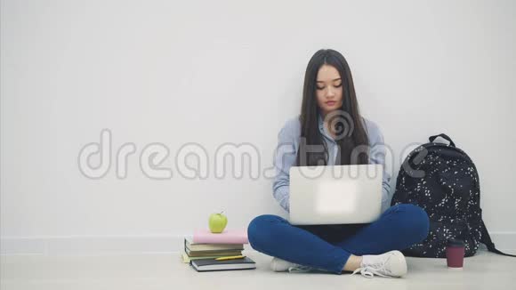 可爱的年轻亚洲女士坐在地板上坐在洛托斯的位置在她的笔记本电脑里寻找东西举起一张纸视频的预览图
