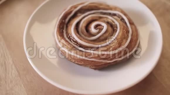 在白色的盘子上用蜂蜜和白色的釉在木制的圆板上旋转视频的预览图