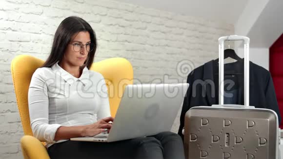 自信的时尚女商人在出差期间使用笔记本电脑视频的预览图