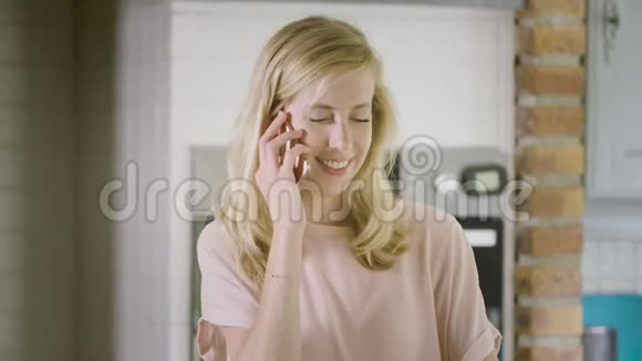 厨房里的女人用智能手机微笑着打电话视频的预览图