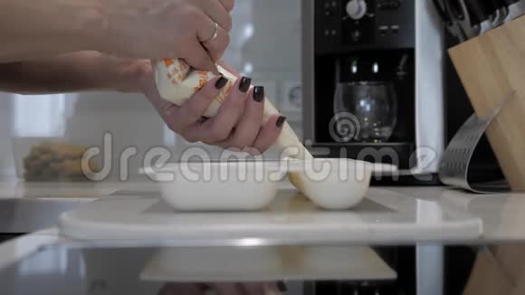 女性的手把白色奶油从糕点袋倒入硅胶模具特写视频的预览图