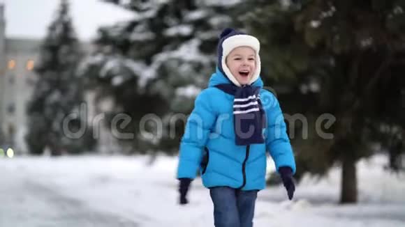 穿着蓝色冬装的可爱的四岁男孩走在雪地里视频的预览图
