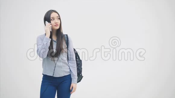情绪激动的年轻亚洲女孩正在打电话讨论一些问题挥动她的手看上去心烦意乱她身上的背包视频的预览图