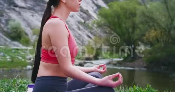 女士穿着舒适的运动服在令人惊叹的风景旁边练习瑜伽冥想视频的预览图