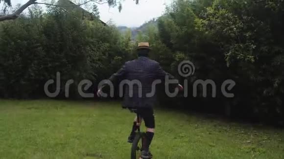 有趣优雅的男人在后院骑独轮车视频的预览图