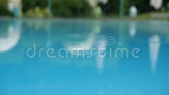 雨滴缓慢地落在游泳池的表面雨溅到蓝色的水池里近距离游泳视频的预览图