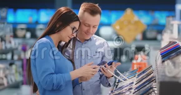 快乐夫妇在科技商店买新的智能手机决定购买哪种型号视频的预览图