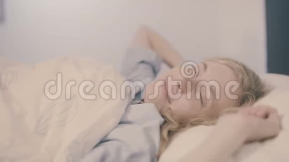 躺在床上的年轻女子醒来时微笑着伸着懒腰看着摄像机视频的预览图