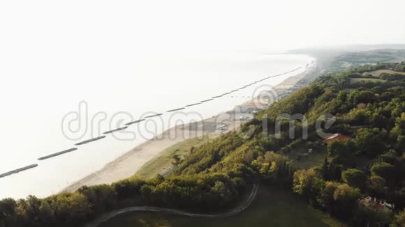 无人机飞越壮丽的夏季地中海沿岸绿树成山和阳光充足的沙滩日景视频的预览图