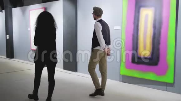 画廊的一对客人正带着照片在大厅里散步视频的预览图