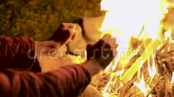 在寒冷的秋夜里年轻人在篝火旁暖和他的手视频的预览图