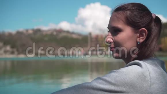年轻女子特写春日坐在湖边在大自然中放松视频的预览图