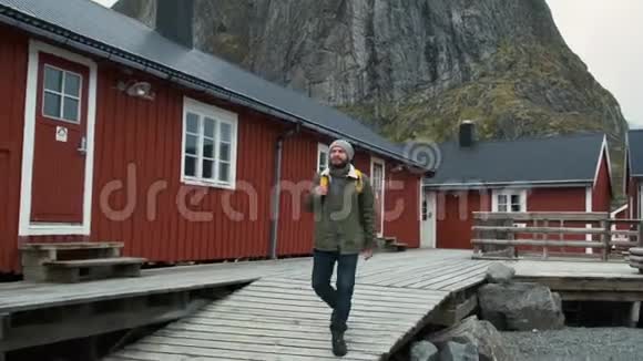 男性游客步行穿过村庄雷恩洛福顿挪威蓝天有典型的罗布房屋男人视频的预览图