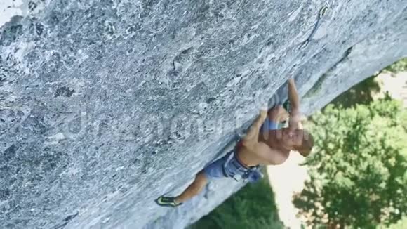 山顶景观年轻强壮的肌肉男攀岩者攀登高垂的石灰石悬崖视频的预览图