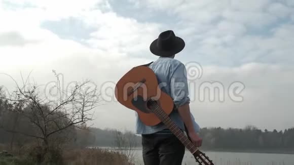 嬉皮士在秋天的森林和湖里弹吉他视频的预览图