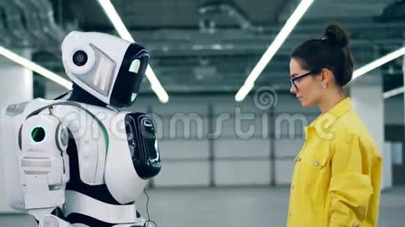 人和现代机器人触摸手站在房间里视频的预览图