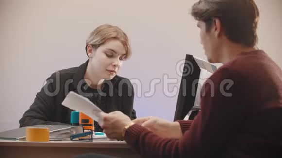 办公室一个女人在告诉文件上写着什么男人在听视频的预览图