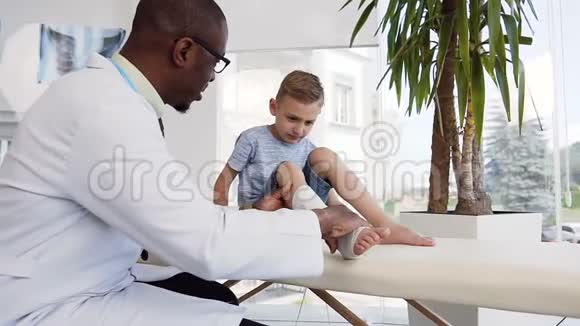男医生检查可爱男孩腿上的绷带视频的预览图