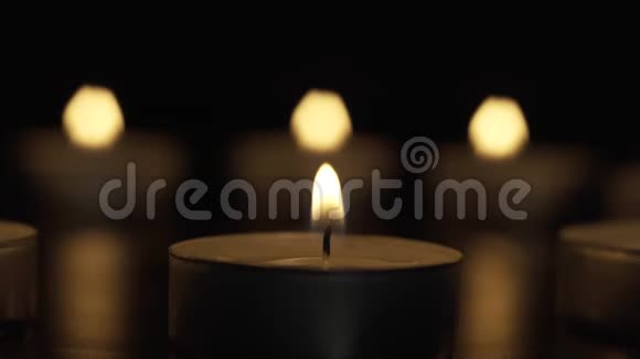 蜡烛在黑暗中慢慢燃烧在三盏灯的背景下视频的预览图