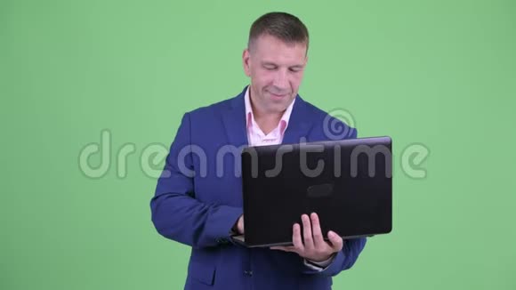 在使用笔记本电脑的时候快乐的成熟男子汉商视频的预览图