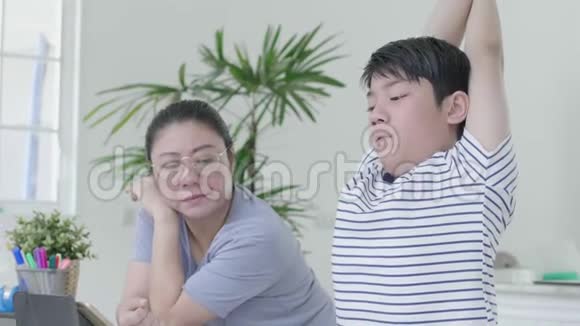 严格的亚洲母亲正在检查儿子家庭作业视频的预览图