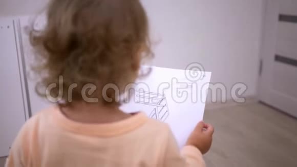 一个拿着奶嘴的小女孩看着组装家具的说明书点点头视频的预览图
