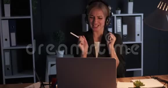 疯狂的女商人在夜间办公室工作时喜欢音乐视频的预览图