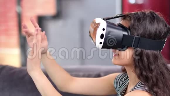 穿着虚拟现实头盔模拟器享受3d网络空间的年轻女士视频的预览图