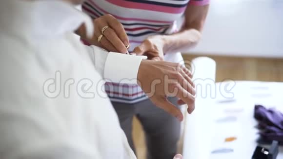 在婚礼当天戴上袖扣亲密的母亲的双手帮助她结婚的儿子做好准备行动视频的预览图
