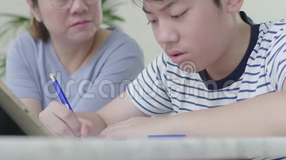 严格的亚洲母亲正在检查儿子教育视频的预览图