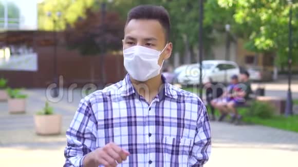 年轻的亚洲男人脸上带着医疗面具咳嗽他用智能手机慢吞吞地说视频的预览图