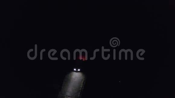 汽车在漆黑的夜晚行驶在乡间的道路上无人驾驶飞机的顶部车灯在黑暗中照亮夜路视频的预览图