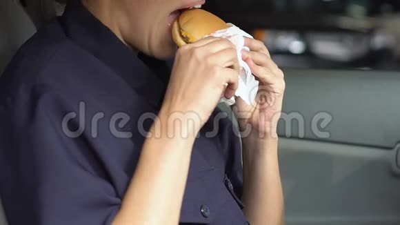 女巡警在车里咀嚼脂肪汉堡饥饿的警官不健康的食物视频的预览图