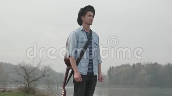 嬉皮士在秋天的森林和湖里弹吉他视频的预览图