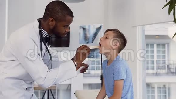 男医生儿科医生耳鼻喉科医生检查可爱的小男孩喉咙视频的预览图