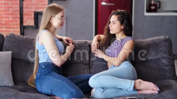 两位美丽的女朋友微笑着坐在豪华公寓的沙发上聊天视频的预览图
