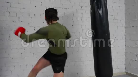 男子拳击手在手套训练踢打袋视频的预览图