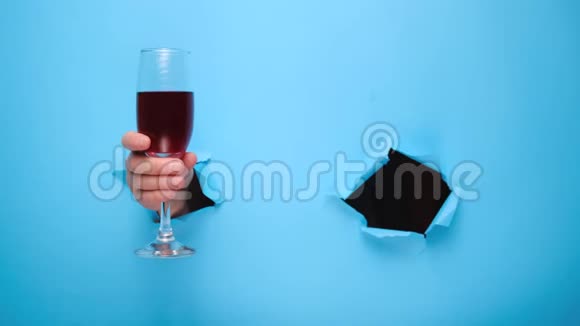 一个女人手里拿着一杯红酒在撕破的蓝色纸墙上显示了一个OK标志视频的预览图