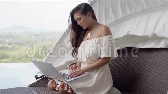 在露台上使用笔记本电脑放松的女士可以看到美丽的风景视频的预览图
