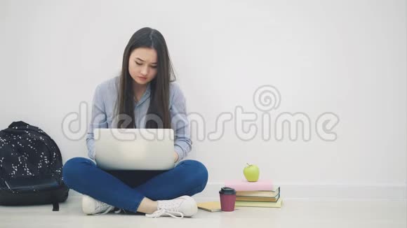 可爱的年轻亚洲女士坐在地板上坐在洛托斯的位置在她的笔记本电脑里寻找东西举起一张纸视频的预览图
