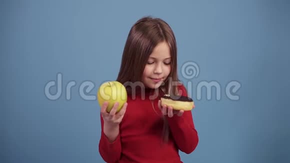 可爱的小女孩选择了一个巧克力圈上面覆盖着五颜六色的喷头和一个绿色的新鲜苹果决定视频的预览图