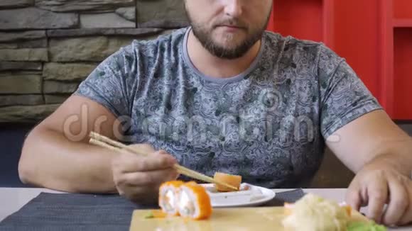 可爱的胖乎乎的男人留着胡子在寿司吧里有趣的吃面包不知道如何处理棍子滚落出来视频的预览图