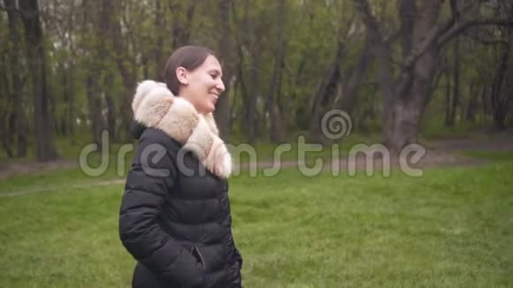 一个穿着暖和的黑色夹克的女孩走路女孩和照相机在平行移动女孩笑了笑视频的预览图