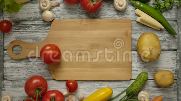 一只雄性手在木切割板上旋转一个红色的番茄视频的预览图