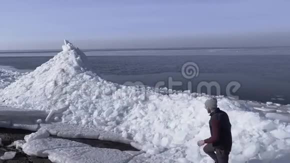 一个年轻活跃的小伙子奔跑着爬上冰川的顶端带着如画般的冬海自然风光视频的预览图