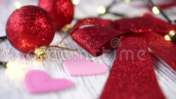 白色木桌上的圣诞树装饰品红弓和球粉红的心视频的预览图