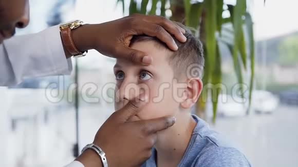 非洲眼科医生检查小男孩的眼睛视频的预览图