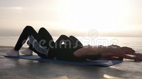 仰卧起坐健身夫妇锻炼身体在外面坐在这些或海洋前面在夏天适合快乐的人工作视频的预览图