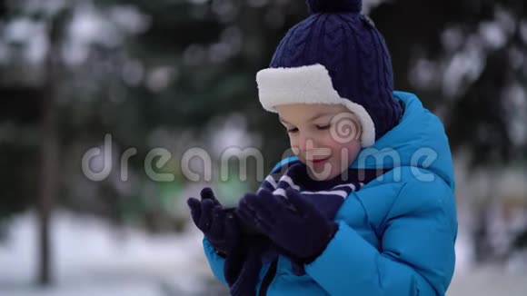 冬天的小男孩在寒冷的雪天穿手机视频的预览图