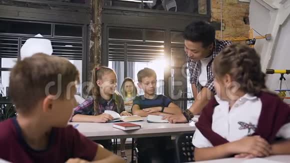白人学生带着韩国教师微笑着看着教科书在课堂上讨论阅读书籍视频的预览图